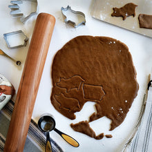 Load image into Gallery viewer, baker&#39;s rolling pin on tabletop with rolled out cookie dough in the shape of pigs and states
