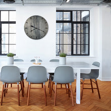 Load image into Gallery viewer, hackberry savanna gallery clock hanging on the wall between two windows behind a table and chairs