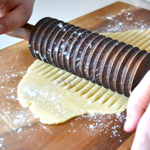 Load image into Gallery viewer, noodle cutter rolling out dough on a cutting board
